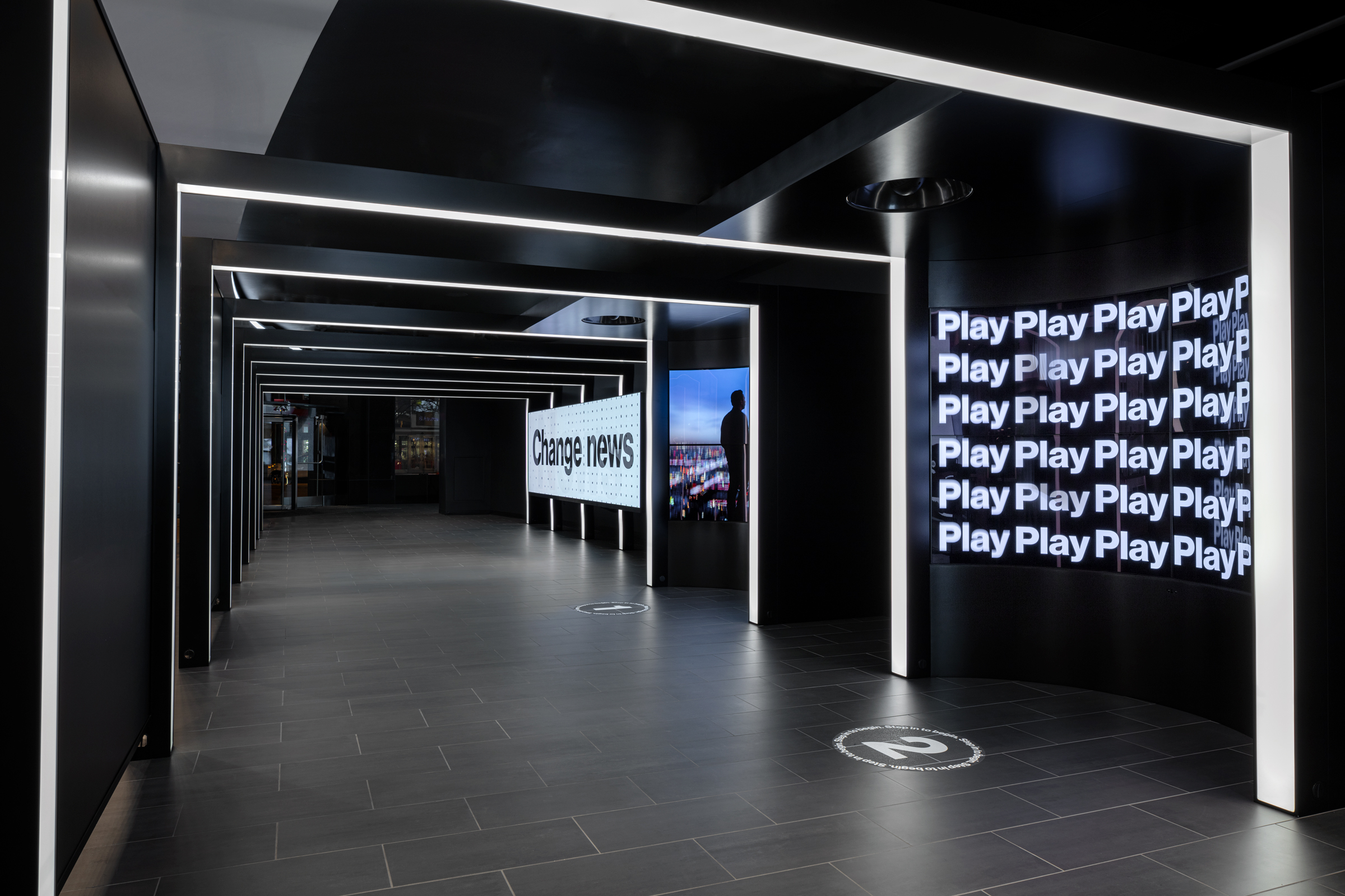 A modern, tech-driven spatial installation for Verizon's 5G pop-up, featuring sleek black-and-white architecture, immersive LED displays, and strategic typography to convey brand identity and futuristic technology through experiential design.